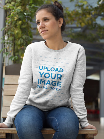 Placeit Woman Sitting on a Bench Wearing a Crew Neck Sweatshirt Template