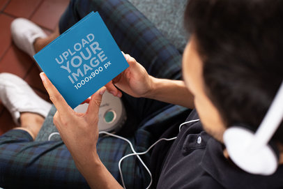 Mockup of a Man Holding a Digipak While Listening to Music 28354
