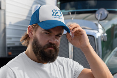 Mockup of a Bearded Man with a Trucker Hat Standing Next to a Truck 29488